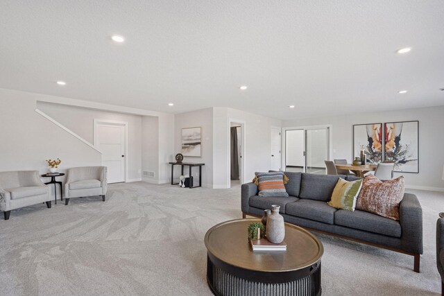 carpeted living room featuring baseboards, visible vents, a textured ceiling, and recessed lighting