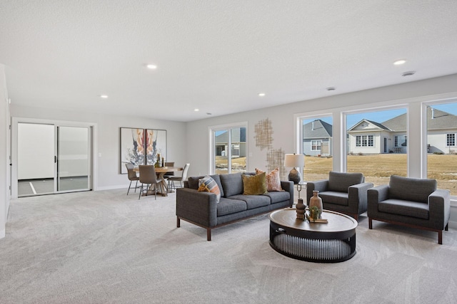 carpeted living area with baseboards, a textured ceiling, and recessed lighting