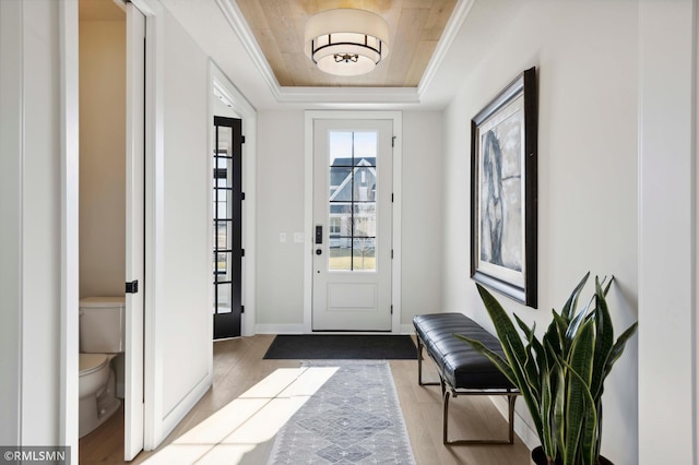 doorway with light hardwood / wood-style floors and a tray ceiling