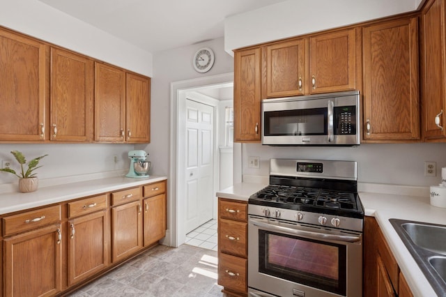 1503 Sheridan Ave N, Minneapolis, MN 55411 - kitchen featuring stainless steel appliances, brown cabinetry, and light countertops