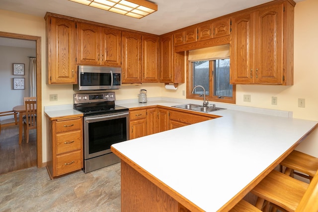 kitchen with appliances with stainless steel finishes, sink, a kitchen bar, and kitchen peninsula