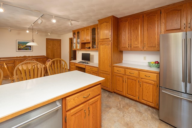 kitchen with pendant lighting, appliances with stainless steel finishes, and built in desk