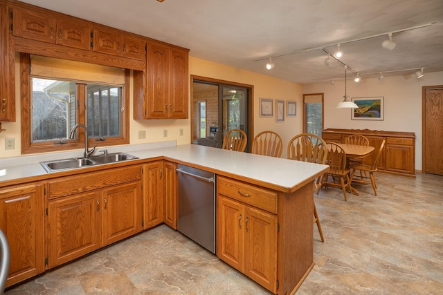 kitchen featuring a kitchen bar, sink, kitchen peninsula, dishwasher, and pendant lighting