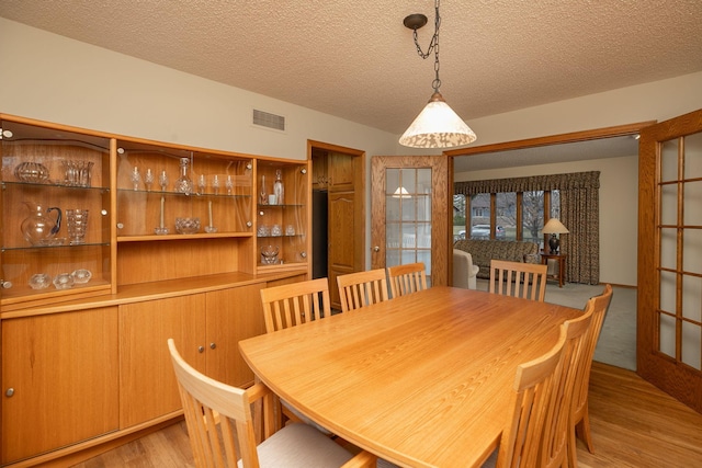 dining area with light hardwood / wood-style floors and a textured ceiling