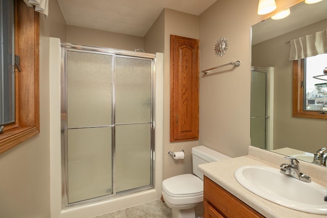 bathroom featuring vanity, a shower with shower door, and toilet