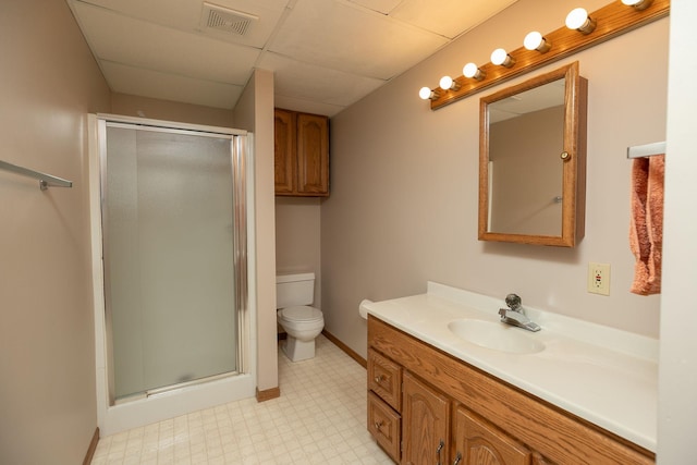 bathroom featuring vanity, a shower with shower door, toilet, and a paneled ceiling