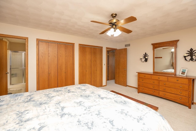 bedroom with multiple closets, ensuite bathroom, light colored carpet, and ceiling fan