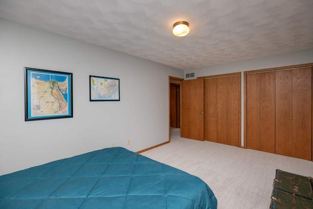 unfurnished bedroom with two closets and light colored carpet