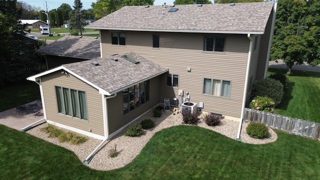 rear view of house featuring central AC unit, a patio area, and a lawn