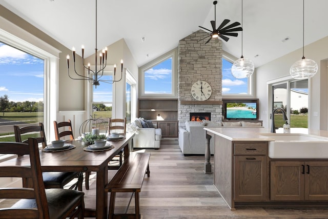 dining room featuring an inviting chandelier, wood-type flooring, a healthy amount of sunlight, and a fireplace