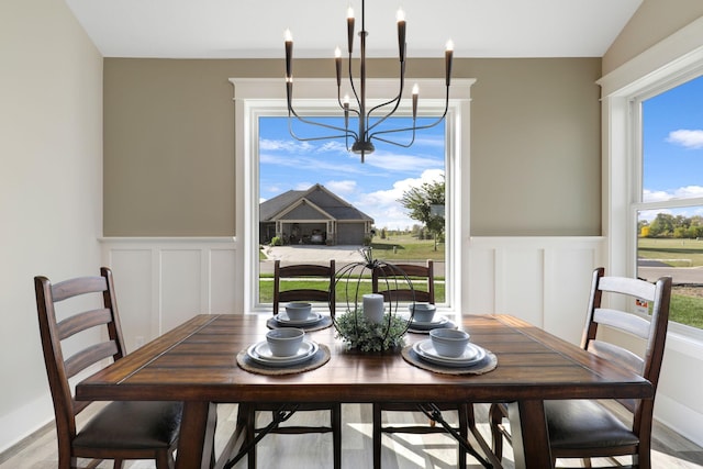 dining space with a notable chandelier, lofted ceiling, and light wood-type flooring