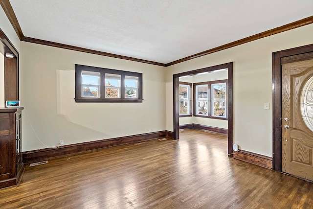 entryway featuring a wealth of natural light, ornamental molding, and dark hardwood / wood-style floors