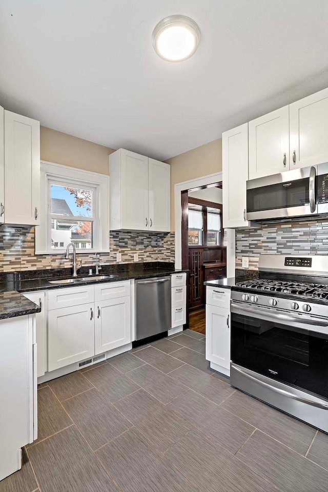 kitchen featuring sink, appliances with stainless steel finishes, decorative backsplash, and white cabinets