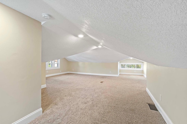 bonus room with lofted ceiling, carpet, and a textured ceiling