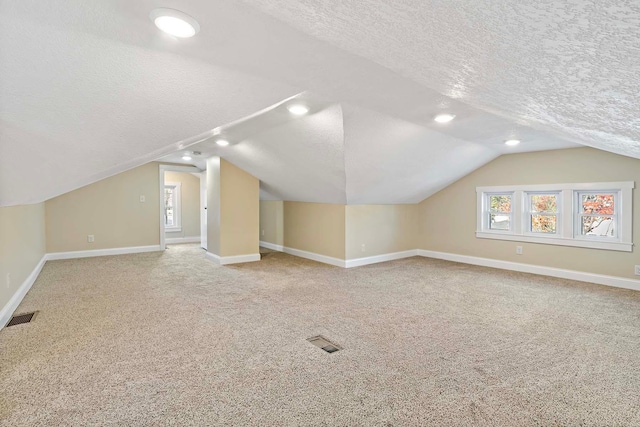 bonus room featuring lofted ceiling, a textured ceiling, and carpet