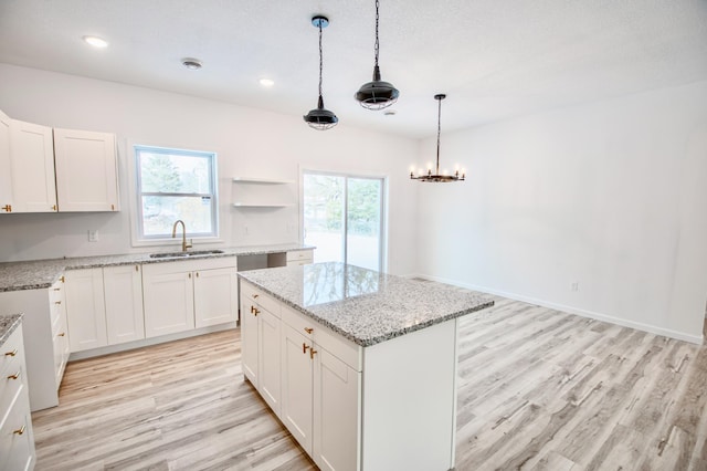 kitchen with white cabinetry, sink, hanging light fixtures, and a center island