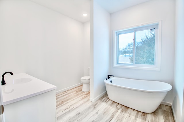 bathroom with toilet, hardwood / wood-style floors, a tub, and vanity