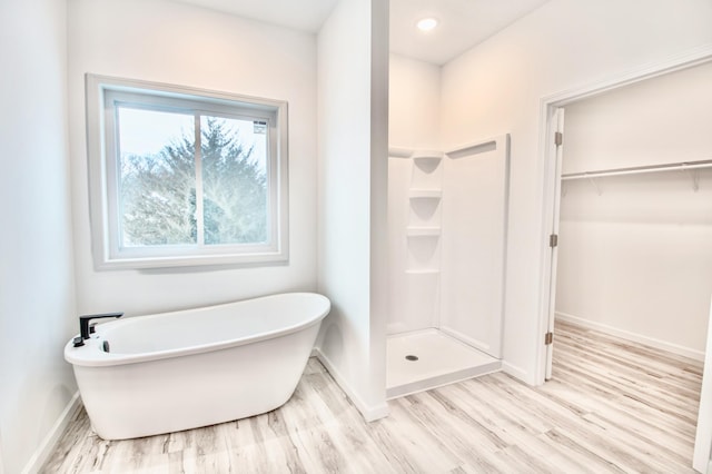 bathroom with wood-type flooring and shower with separate bathtub