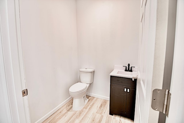 bathroom with toilet, hardwood / wood-style flooring, and vanity