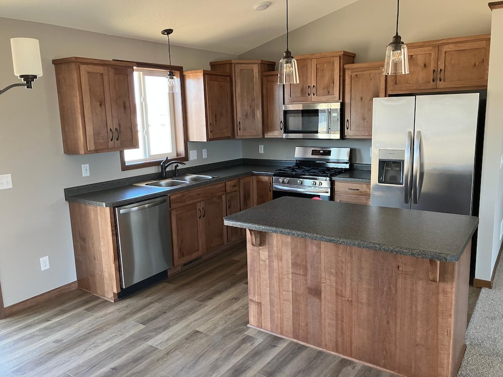 kitchen with decorative light fixtures, appliances with stainless steel finishes, light wood-type flooring, and sink