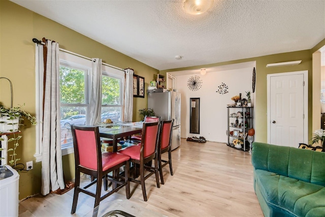 dining area featuring a textured ceiling and light wood-type flooring