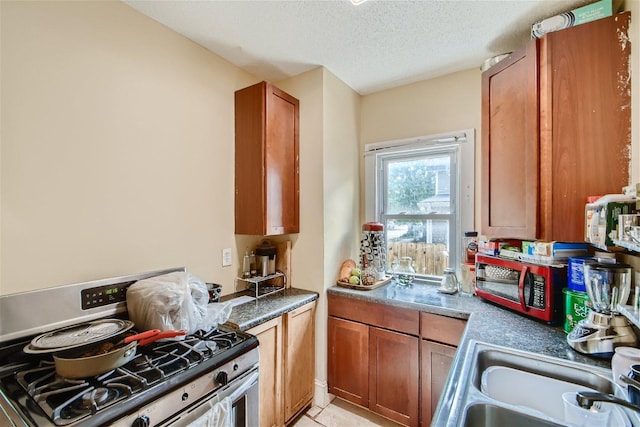 kitchen featuring light tile flooring, sink, stainless steel appliances, and a textured ceiling