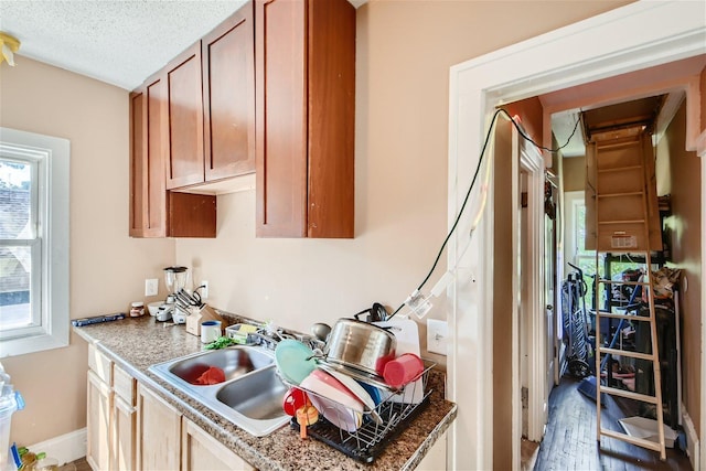 kitchen with dark stone countertops, sink, a textured ceiling, and hardwood / wood-style flooring