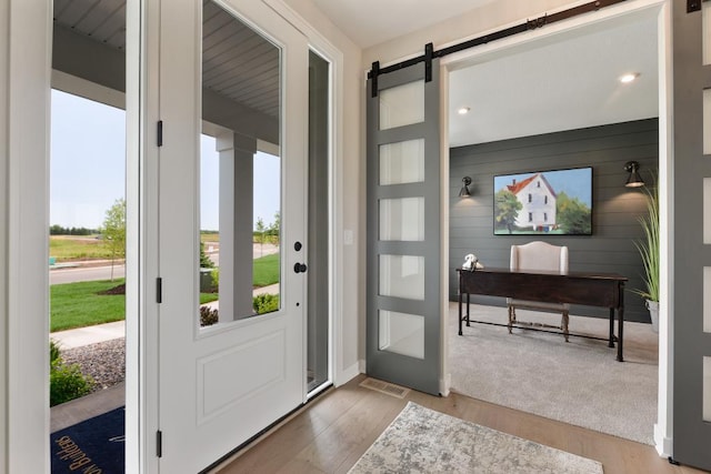 doorway with light colored carpet and a barn door