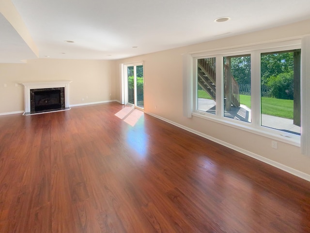 unfurnished living room with a healthy amount of sunlight, a high end fireplace, and dark hardwood / wood-style flooring