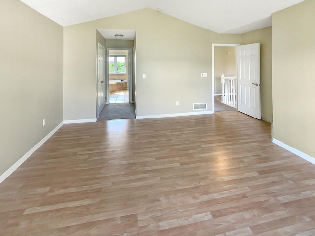 spare room featuring lofted ceiling and wood-type flooring