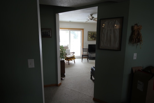 hallway with light colored carpet and a textured ceiling