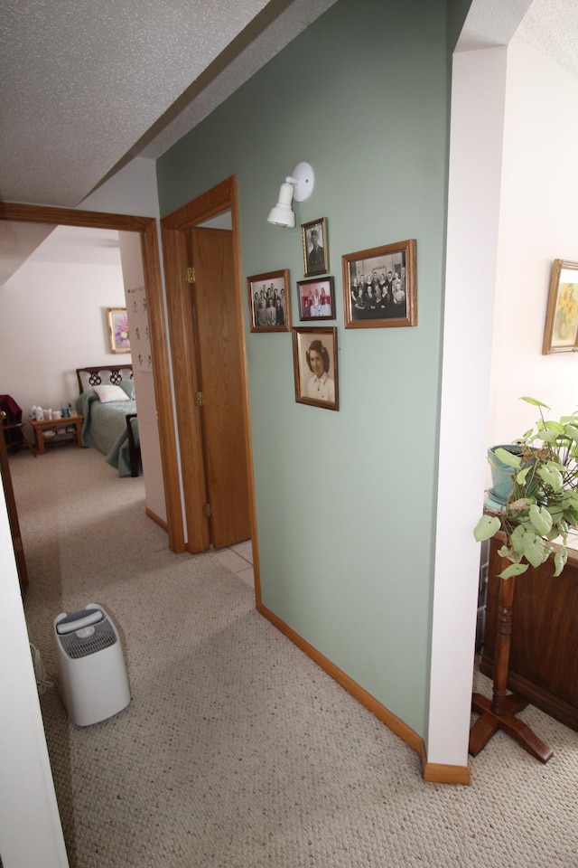 hall featuring a textured ceiling and light carpet