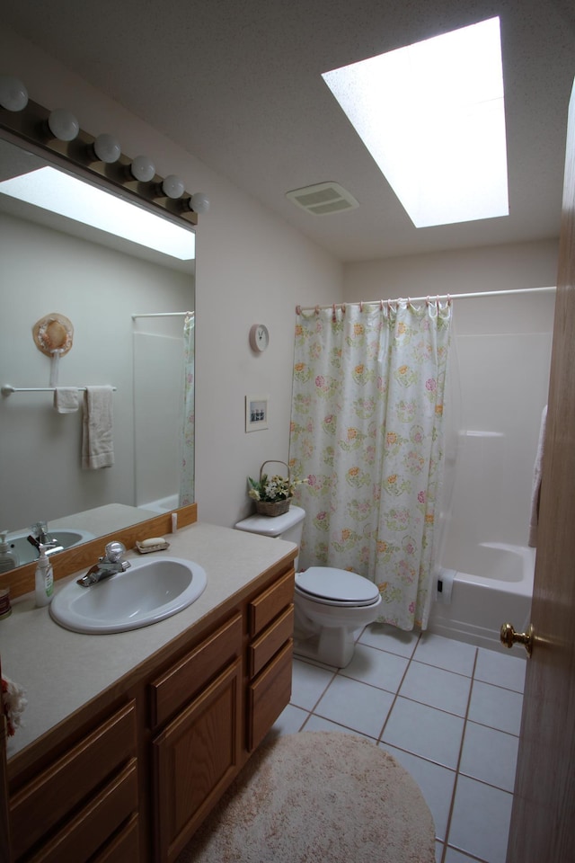 full bathroom with shower / bath combo with shower curtain, large vanity, tile flooring, a skylight, and toilet