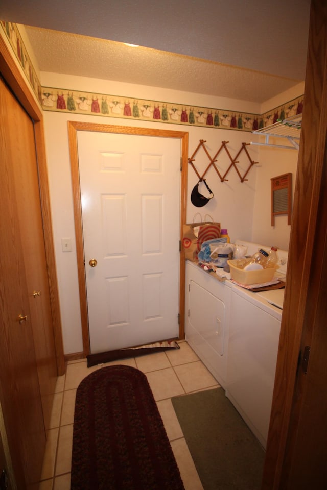 washroom featuring light tile flooring, independent washer and dryer, and a textured ceiling