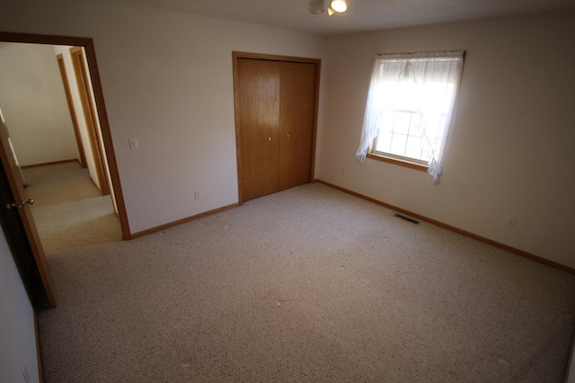 unfurnished bedroom featuring light colored carpet and a closet