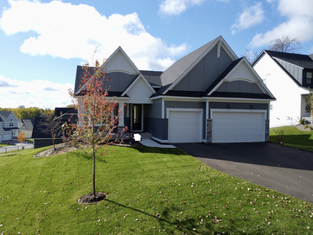 view of front facade featuring board and batten siding, driveway, and a front lawn