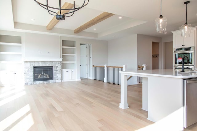 kitchen with pendant lighting, built in features, light hardwood / wood-style flooring, and white cabinetry