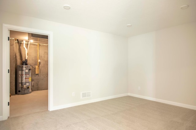 spare room with light colored carpet and gas water heater