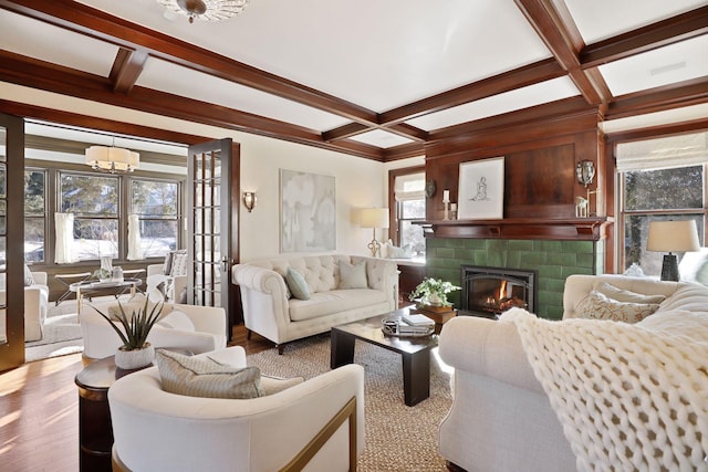 living room with a notable chandelier, beamed ceiling, coffered ceiling, and a tile fireplace