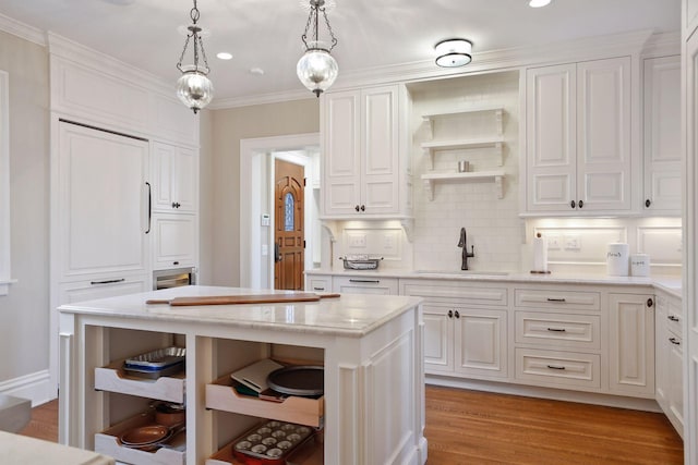 kitchen with decorative light fixtures, white cabinets, a center island, and sink