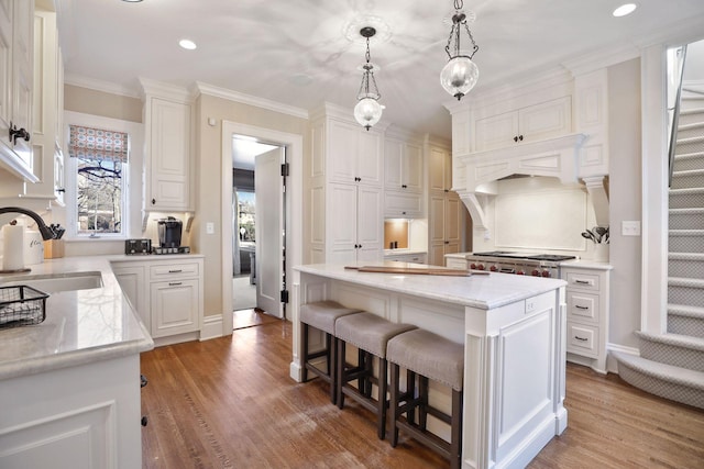 kitchen featuring decorative light fixtures, sink, white cabinetry, and a center island