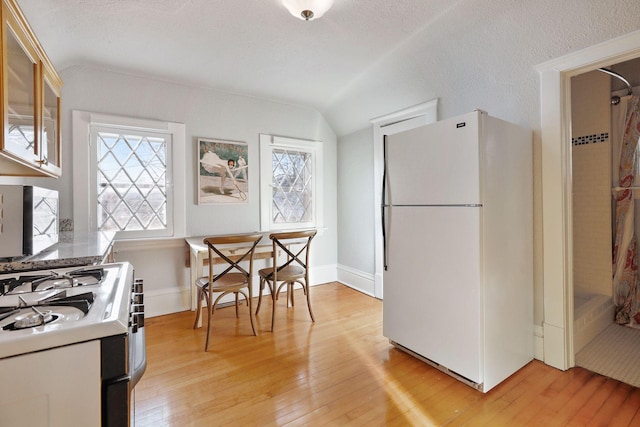 kitchen featuring lofted ceiling, white fridge, light hardwood / wood-style flooring, a textured ceiling, and range with gas stovetop