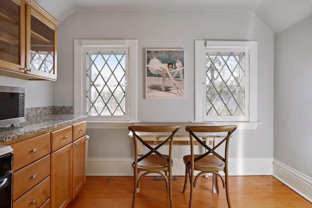 dining room with vaulted ceiling and light hardwood / wood-style floors