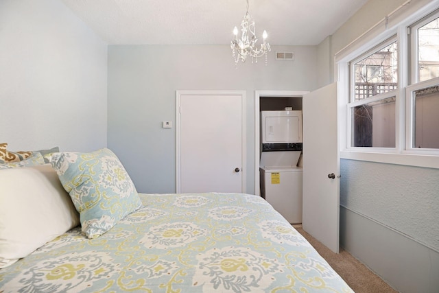 bedroom featuring stacked washer and clothes dryer, a chandelier, and carpet flooring