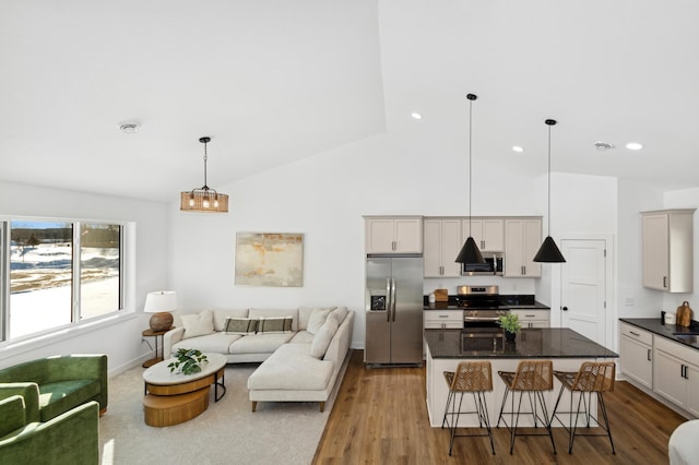 kitchen with a breakfast bar area, stainless steel appliances, a center island, light hardwood / wood-style floors, and decorative light fixtures