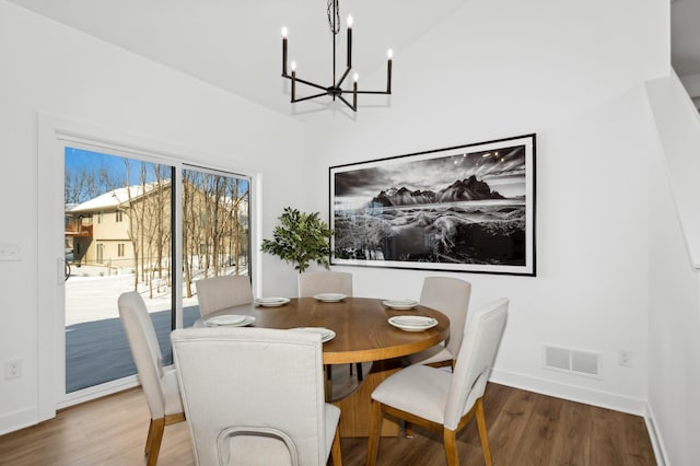 dining area featuring hardwood / wood-style floors, a notable chandelier, and vaulted ceiling