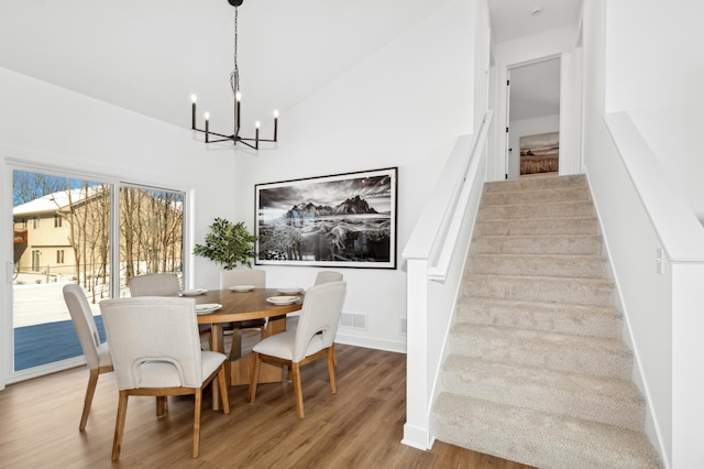 dining room with a notable chandelier, hardwood / wood-style flooring, and vaulted ceiling