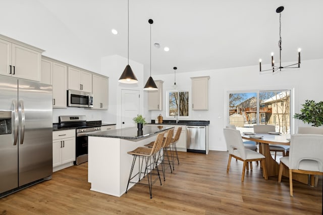 kitchen with sink, hardwood / wood-style flooring, stainless steel appliances, a center island, and decorative light fixtures