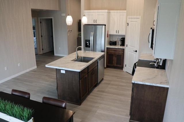 kitchen featuring a kitchen island with sink, sink, white cabinets, light hardwood / wood-style flooring, and stainless steel appliances