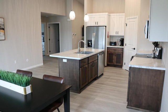 kitchen featuring hanging light fixtures, appliances with stainless steel finishes, sink, light hardwood / wood-style flooring, and white cabinets